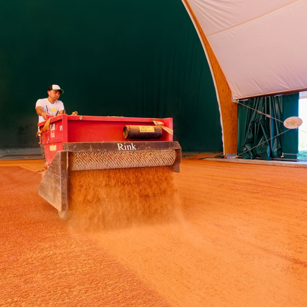 Onderhoud van een rode gravelbaan van RedPlus met een professionele machine